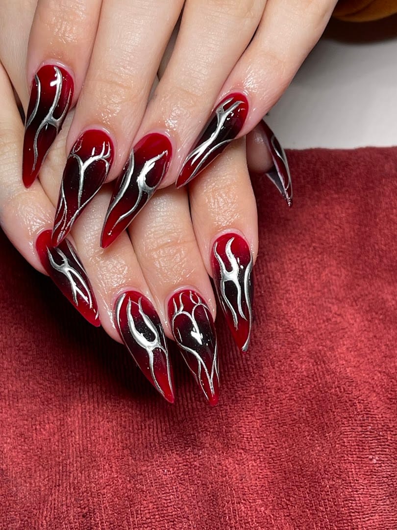 Stiletto red and black nails with silver chrome flame design