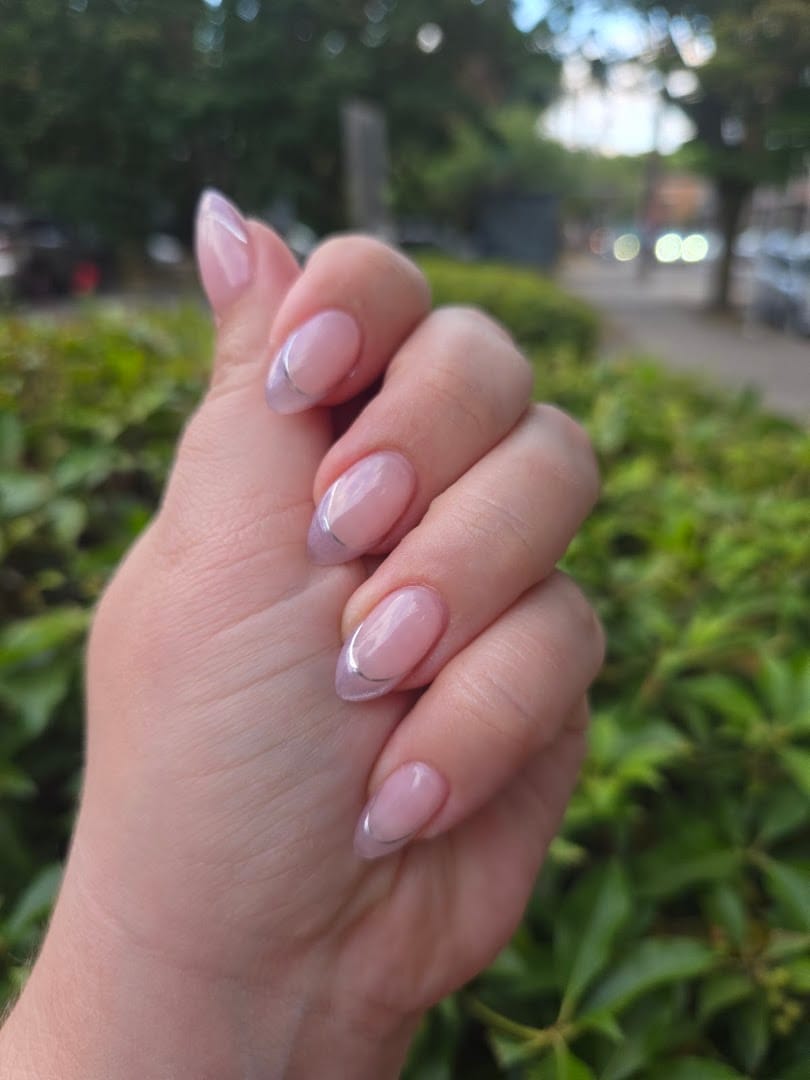 Hand with neat oval French tip manicure against green background